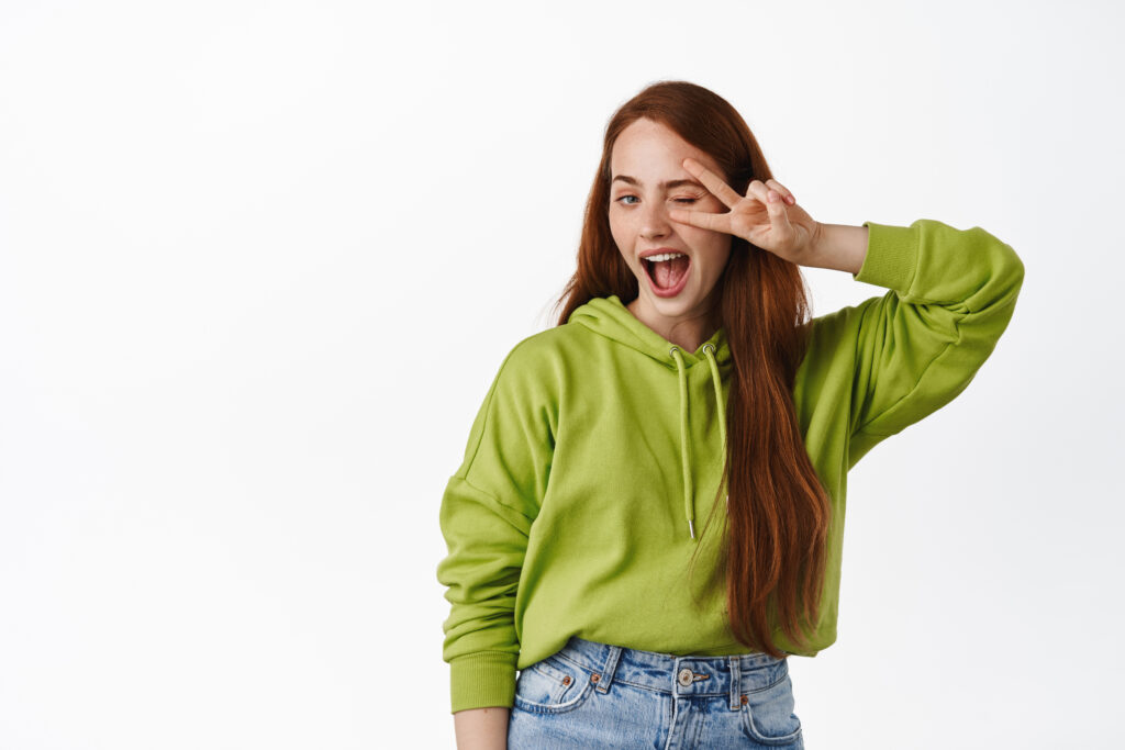 La imagen actual no tiene texto alternativo. El nombre del archivo es: chica-positiva-con-largo-cabello-rojo-natural-muestra-gesto-de-signo-de-paz-v-cerca-de-guino-de-ojo-sonriendo-feliz-posando-en-traje-casual-en-blanco-scaled.jpg